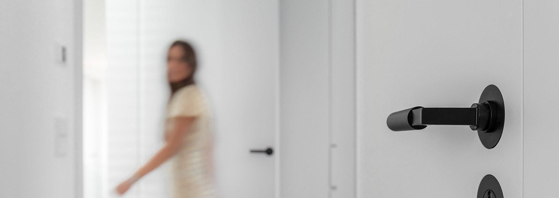 Mood-Bild flächenbündiger Drücker in einem Flur, Frau läuft im Hintergrund vorbei