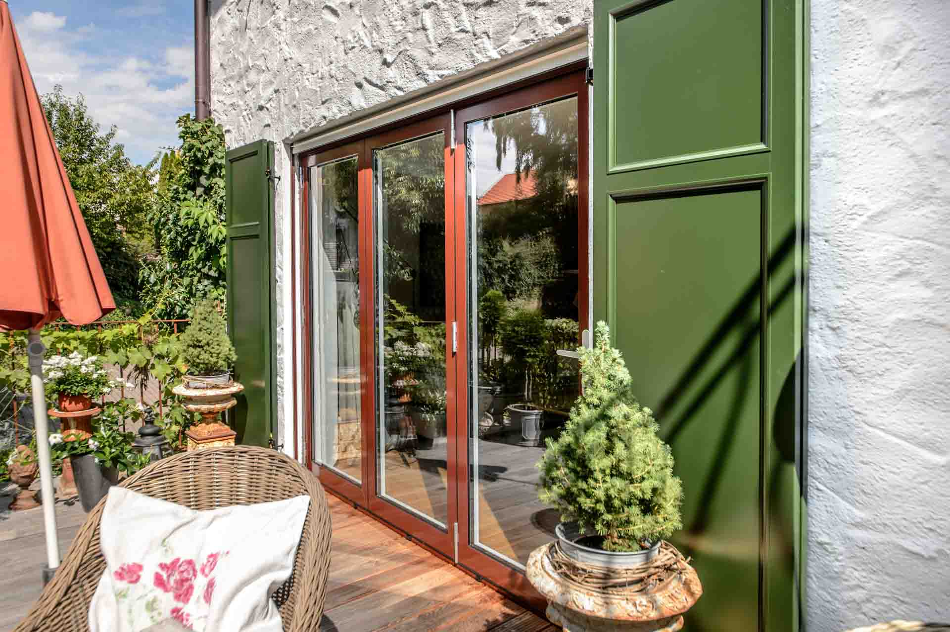 Dreiteilige Hebeschiebetür auf der Terrasse mit dunkelgrünen Fensterläden in Haag an der Amper.