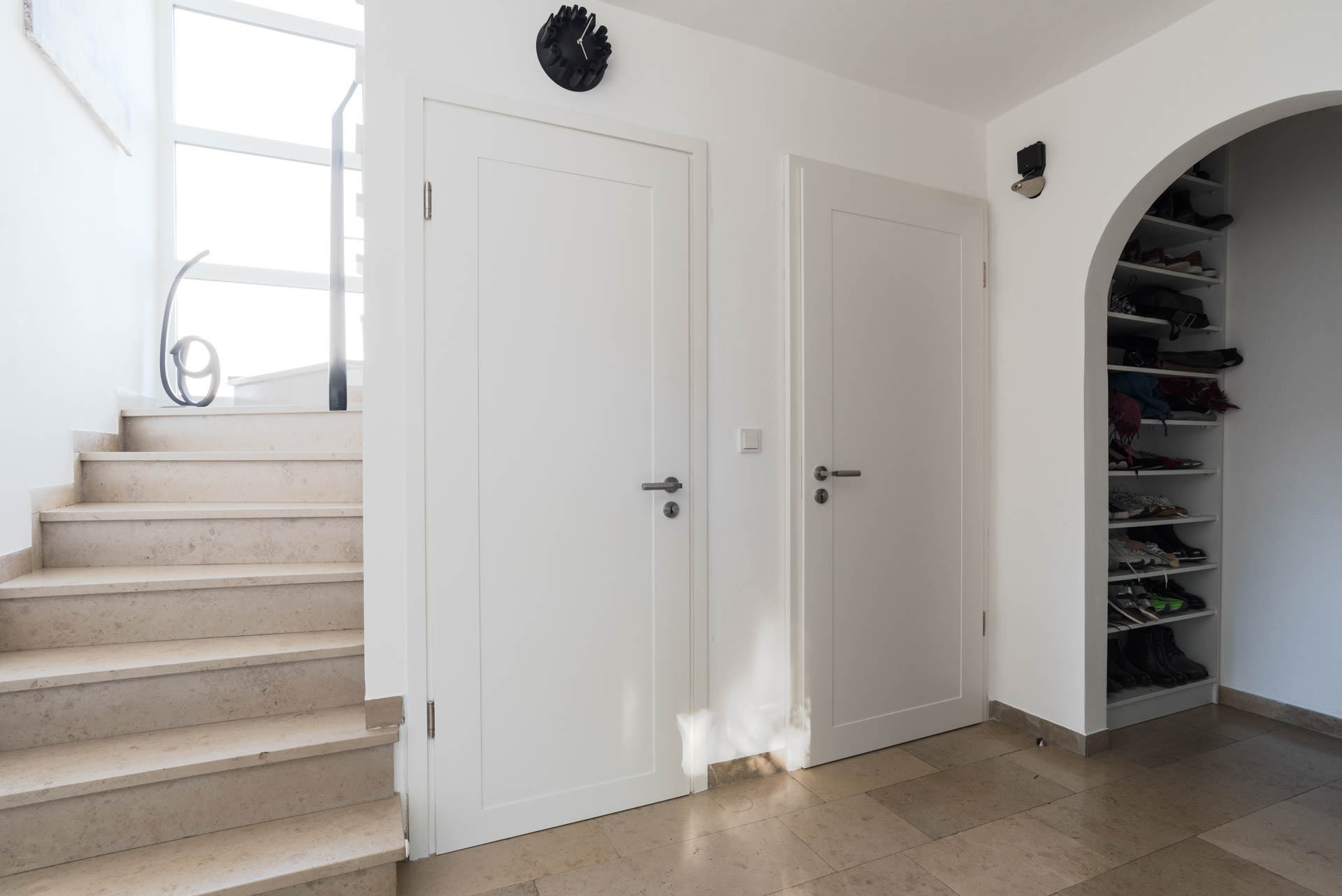 Zwei schlichte weiße Innentüren neben einer Steintreppe in München.