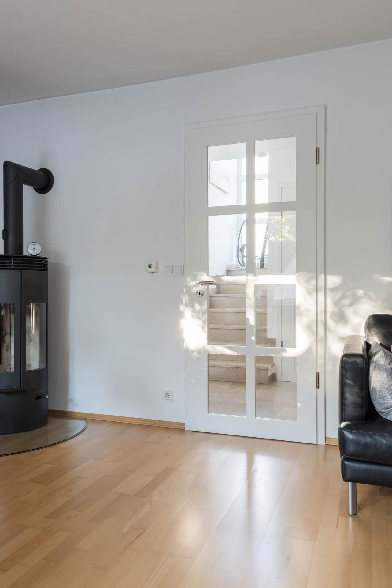 Innentür mit Glasausschnitt und Sprossen neben einem modernen Ofen.