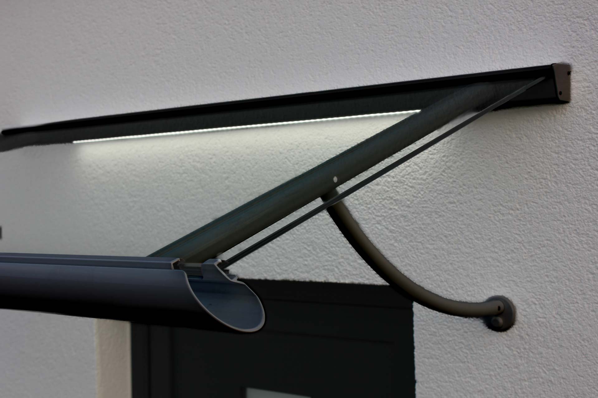 Anthrazitfarbenes Vordach mit Regenrinne, Stahlseil-Halterung und integrierter LED-Lichtleiste.