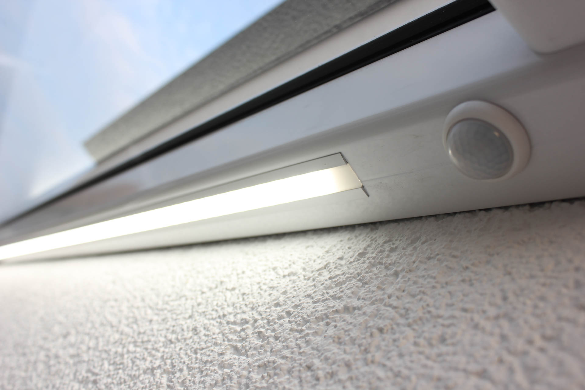 Detailansicht der integrierten LED-Beleuchtung und des Bewegungsmelders an einem modernen Vordach.