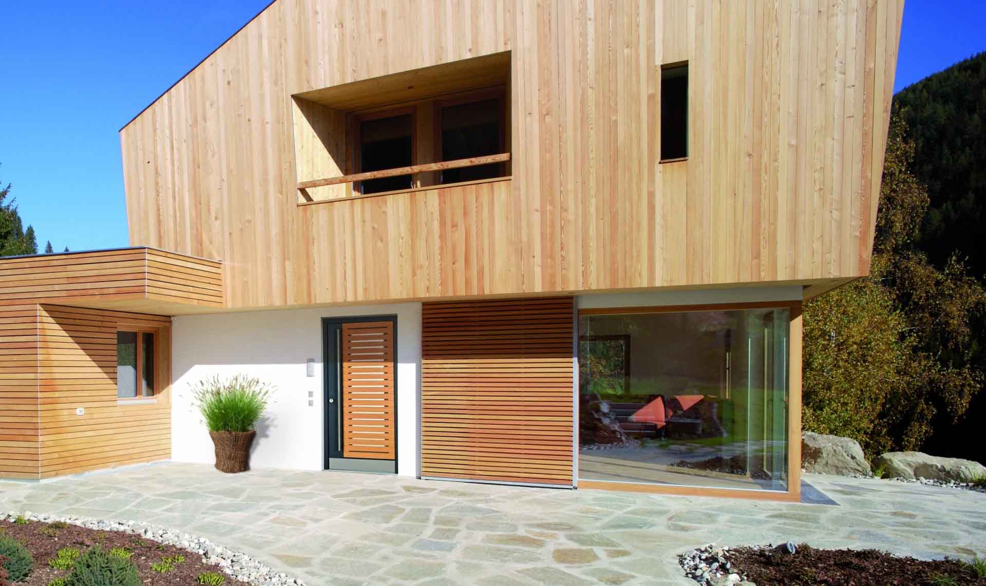 Exklusive Holz-Haustür in Lärche mit schmalen Lichtschlitzen und vertikaler Verkleidung an einem modernen Holzhaus.