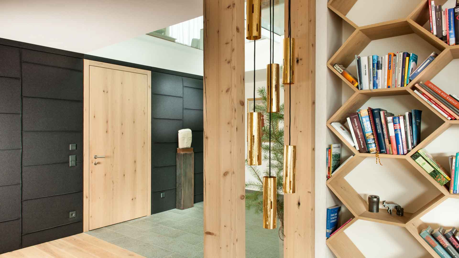 Natürliche Holz-Wohnungseingangstür in heller Eiche in einem modernen Eingangsbereich mit schwarzem Wand-Design.