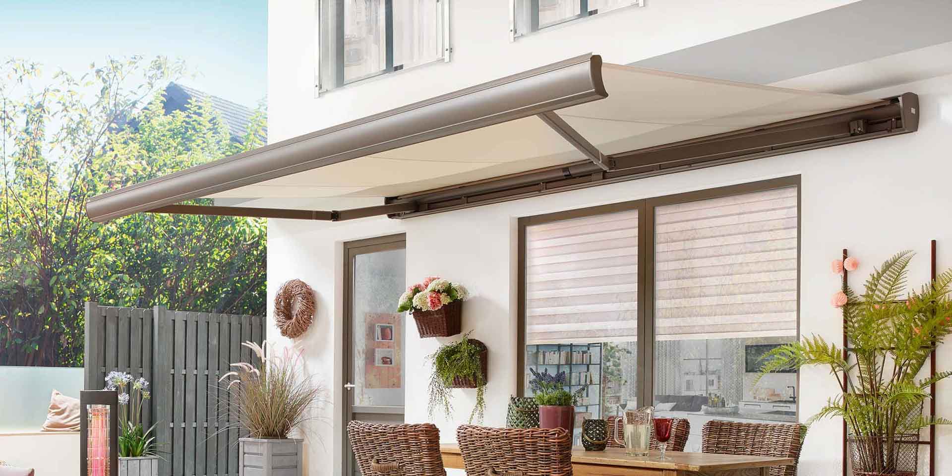 Elegante, braune Gelenkarmmarkise mit beigem Stoff als Sonnenschutz über dem Essbereich der Terrasse.