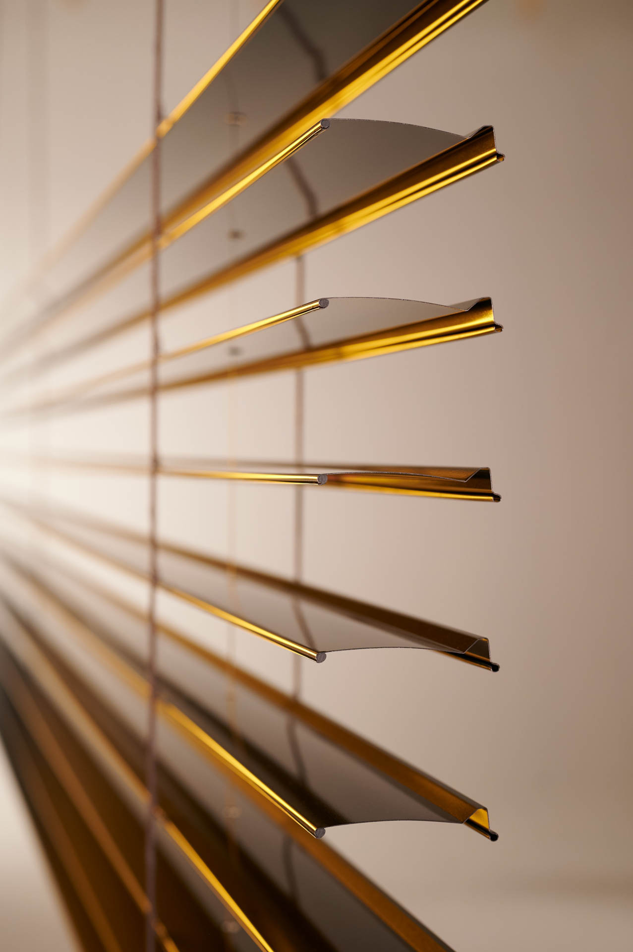 Nahaufnahme der horizontalen, golden glänzenden Raffstore-Lamellen von unten gesehen.