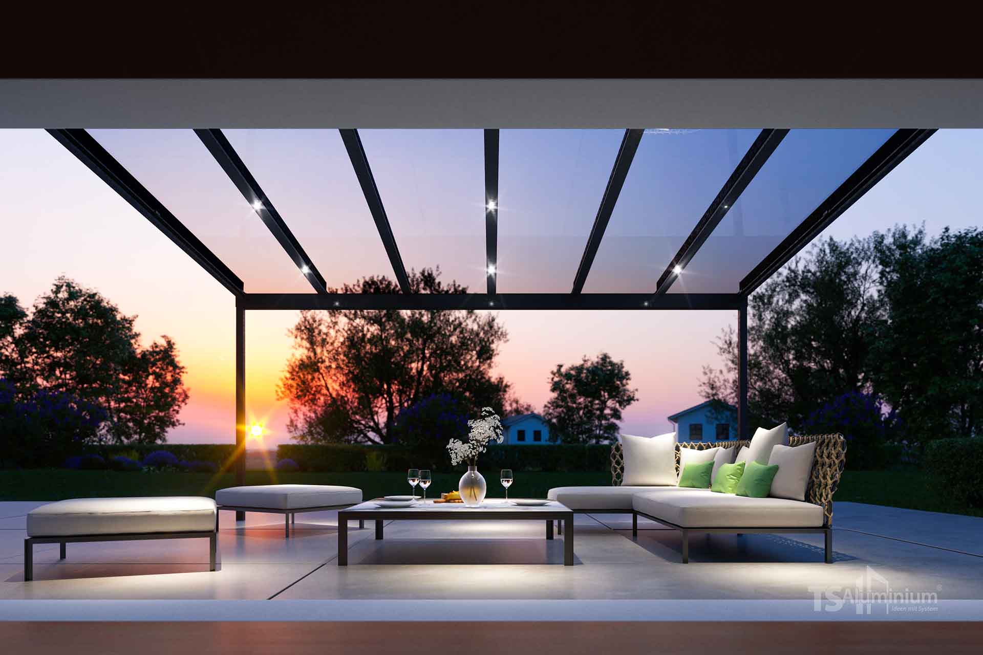 Gemütliche Lounge-Terrasse unter einem Terrassendach mit Glasdach und Spots, beleuchtet bei Sonnenuntergang.