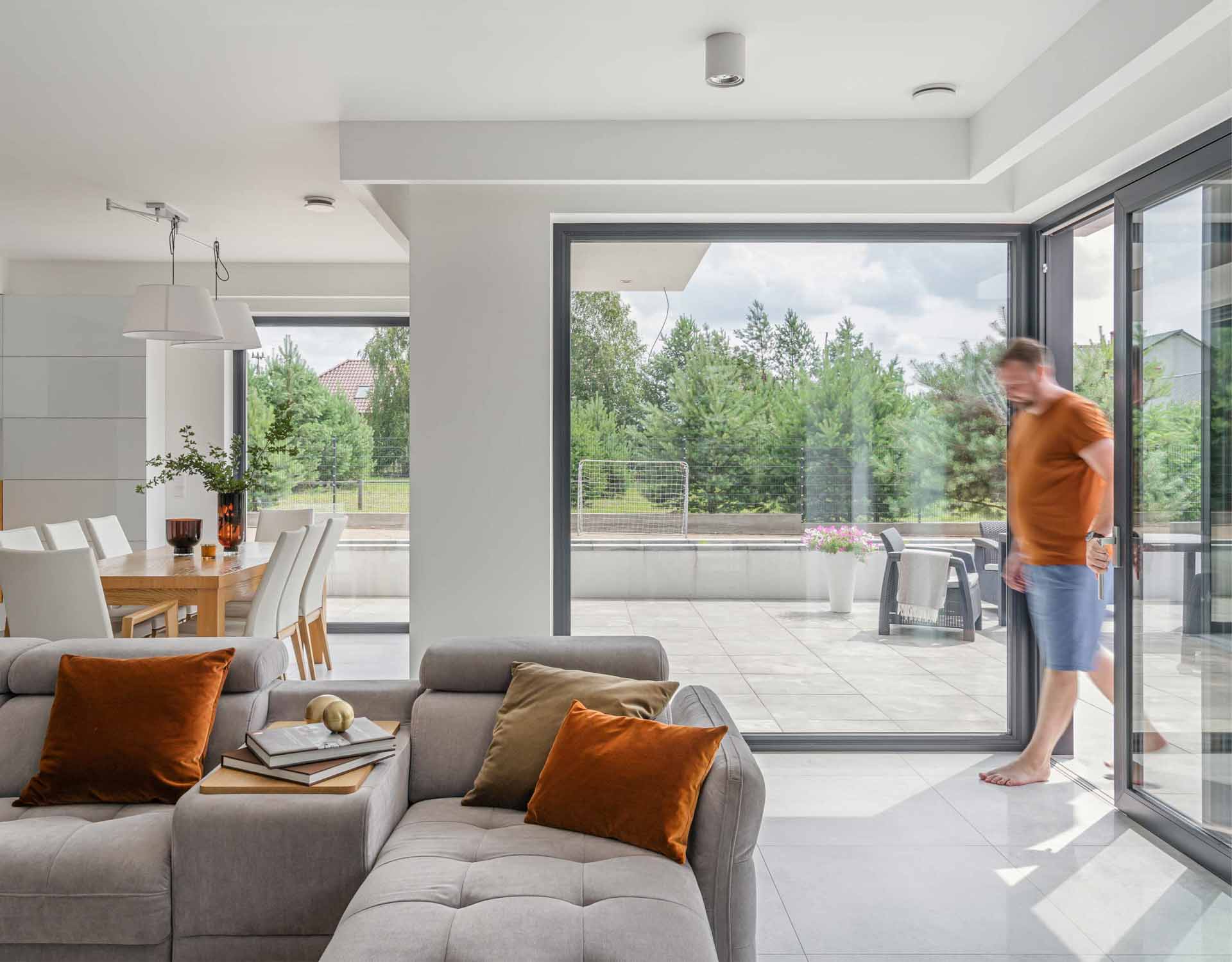 Offener Wohnbereich mit zwei schwarzen Kunststoff-Terrassentüren und großen Verglasungen, die viel Licht bieten.